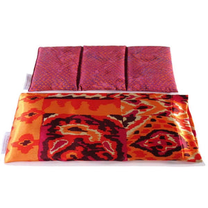 A heating pad with a satin cover in an orange, brown and red native American print. Behind the pad is a cotton insert sewn in three sections to hold the organic flaxseed in place. The insert has a rust and pink cover.