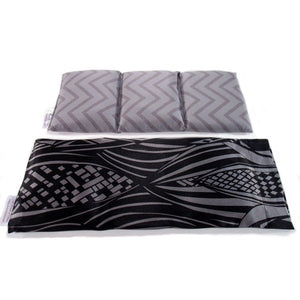 A heat wrap with a black and gray modern print cover. Behind the wrap is a cotton insert that is sewn in three sections. There is a wavy light and dark gray cover on the insert.